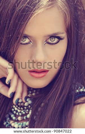 beautiful young woman with cat eye liner make-up and grey metallic manicure wear coral lipstick.