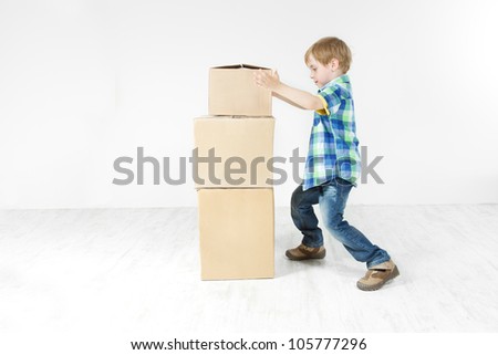 Boy building pyramid of carton boxes. Packing up to move. Growth concept.