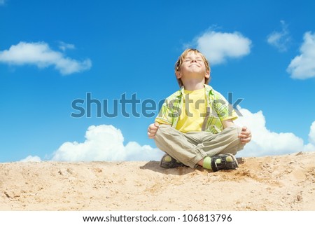 Happy Child Positive Think, Boy Sitting in Yoga Lotus position over blue sky on the top. Kid  Happiness concept.