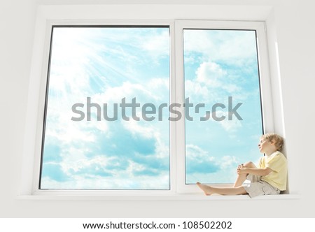 Child sitting on window, enjoying sunshine and dreaming. Big window and sky.