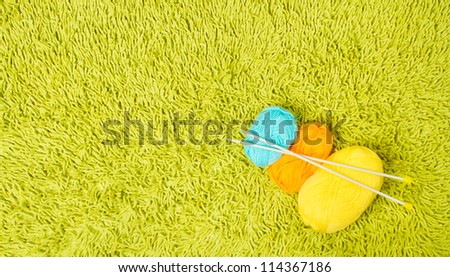 Knitting yarn balls and needles over green carpet background