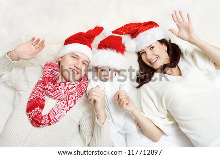 Christmas family of three persons in red hats. Happy parents and small funny baby