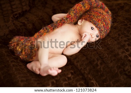 Newborn baby portrait in woolen hat, new born on brown background