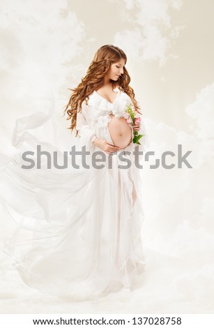 Pregnant woman. Beautiful pregnancy: long curly hair and chiffon dress fluttering on wind.
