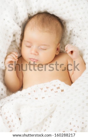 Baby newborn sleeping covered with white woolen blanket