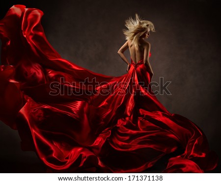 Woman in red waving dress with flying fabric. Back side view