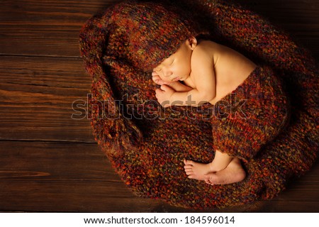 baby newborn portrait, new born kid sleeping in woolen hat on brown wooden background