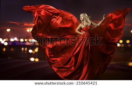 woman dancing in silk dress, artistic red blowing gown waving and flittering fabric, night city street lights