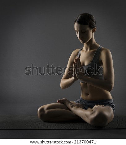 Yoga woman meditate sitting in lotus pose. Silhouette of exercise girl over black background.