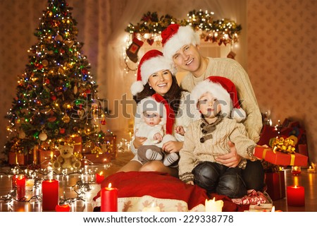 Christmas Family Portrait In Home Holiday Living Room, Kids and Baby at Santa Hat With Present Gift Box, House Decorating By Xmas Tree Candles Garland