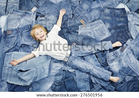 Happy Child Lying on Jeans Clothes Background. Denim Fashion