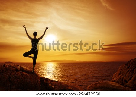 Yoga Meditation Concept, Woman Silhouette Meditating in Nature, Female Back view on stone coast looking to sunset sea