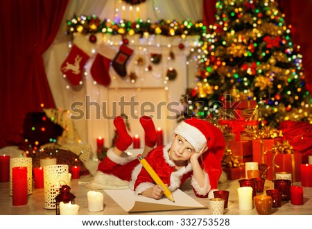 Christmas Kid Write Wish List, Child in Santa Claus Hat Writing Letter, Boy in Holiday Room lying under Christmas Tree