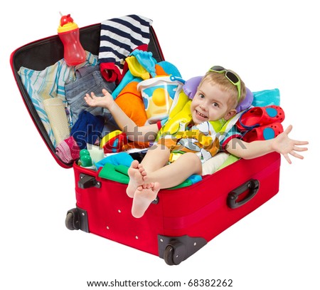Little kid in travel red suitcase. Packed for vacation in sea resort. Personal belongings: hat, cream, towel. Isolated on white