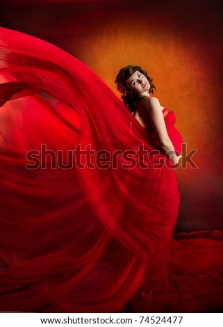 Pregnant woman in red dress waving flying on a wind flow