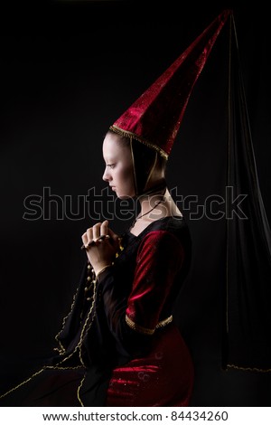 Medieval style portrait of a beautiful  woman in historical costume. low key. Looking down. Stage make up