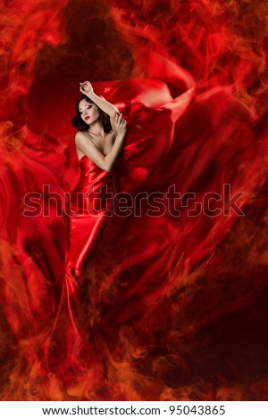 Woman in red waving silk dress as fire flame. Artistic Beauty Model girl posing in flying long gown
