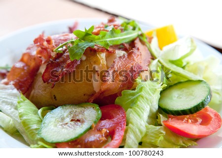 Jacket potato with sour cream and grated cheese on green salad