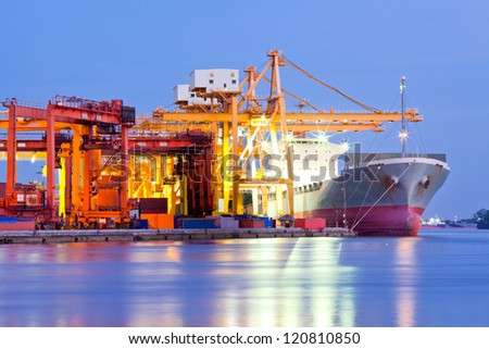 Industrial Container Cargo freight ship with working crane bridge in shipyard at dusk for Logistic Import Export background Industrial Container Cargo freight ship with working crane bridge in shipyard at dusk for Logistic Import Export background