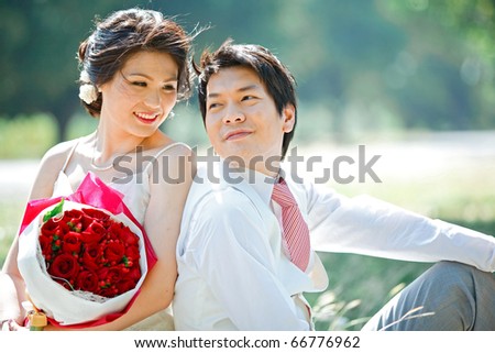 portrait of bride and groom making eye contact with rose bouquet