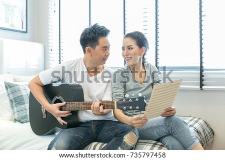 Young Couples playing guitar tohether in bedroom of contemporary house for modern lifestyle concept