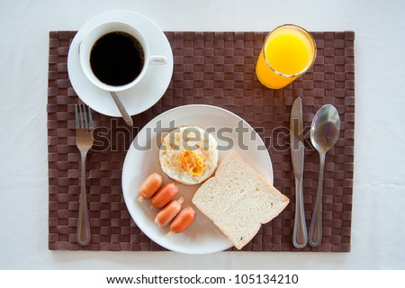 Set of breakfast : American Breakfast set with fried egg, sausages, bread, orange juice and a cup of coffee