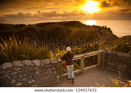 Unidentified girl look beautiful landscape of sea and pancake rock in sunset times, Pancake Rock, South Island, New Zealand