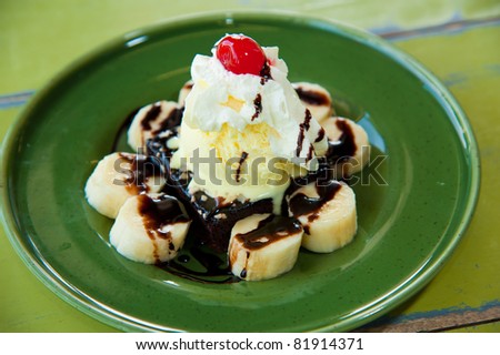 one scoop of vanilla ice-cream topping with banana, cream, red jelly and chocolate