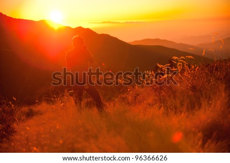 Unidentified man stand and take photo a beautiful view of grass field and Himalayan mountains in sunrise time at the top of Poonhill peak, Nepal