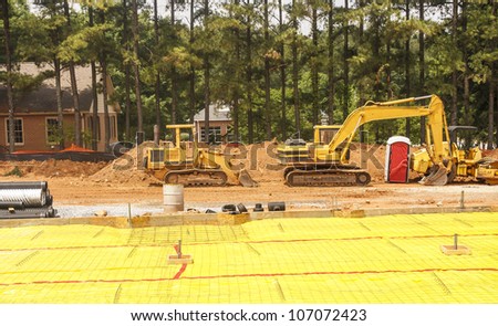 Two pieces of yellow construction equipment on a graded job site