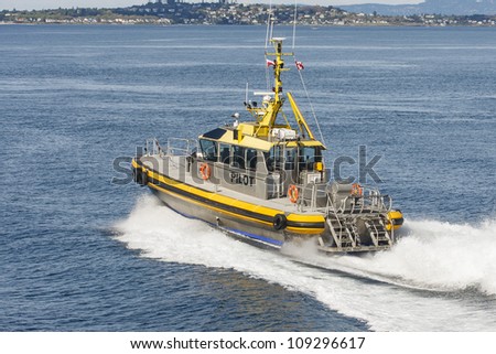 A silver and yellow pilot boat leaving wake behind in blue water