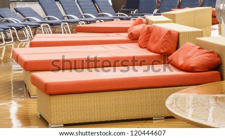 Orange and blue chaise lounges on a ship\'s deck in the rain