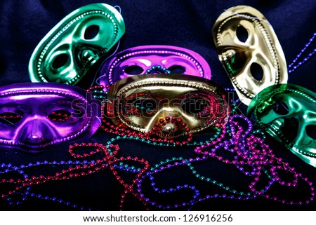 Gold, purple and gold mardi-gras masks with beads on black