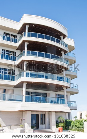 A modern white condo building in the tropics with large balconies