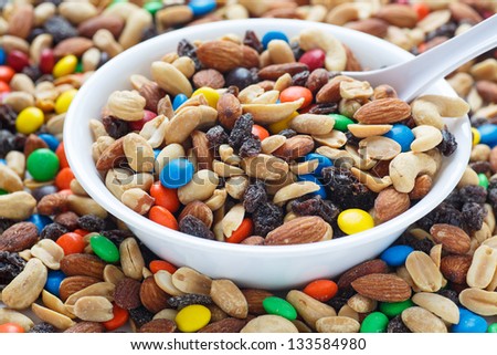 Colorful trail mix in a white bowl with spoon