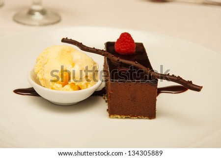 Chocolate brownie garnished with raspberry and a dish of vanilla ice cream
