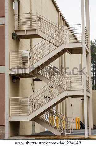 Brown metal stairs ascending in zig-zag pattern up building