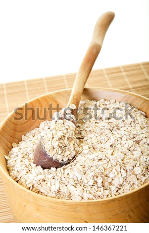Fresh oats in a wood bowl with a wood spoon