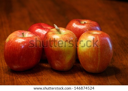 Five red apples on a wood table