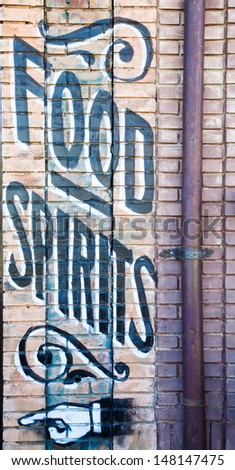 Painted sign on old brick wall for food and spirits