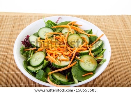 Fresh salad in white bowl of lettuce, greens, spinach, arugula, cucumbers, carrots