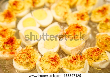 Traditional devilled eggs garnished with paprika on a glass serving dish