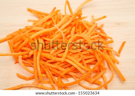 Fresh shredded carrots on a wood cutting board