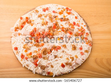 A frozen pizza ready to cook on a wood board