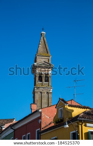 n old church bell tower over brightly colored homes in Burano