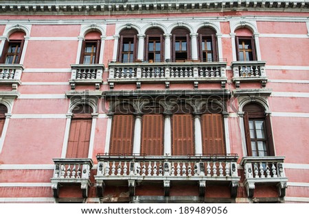 An old plaster hotel in Venice with brown shutters