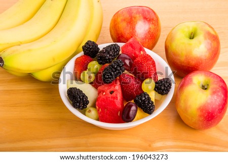 A bowl of fresh cut fruit with whole fruit