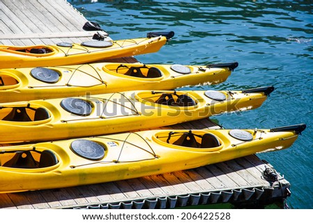 Four yellow kayaks on a wood pier overhanging blue water