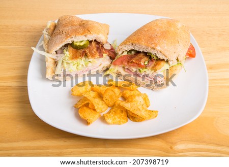 A fresh, sub sandwich on a plate with potato chips