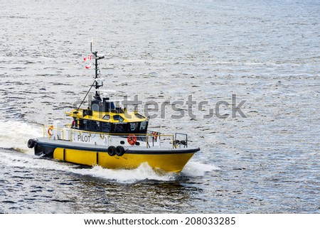 A bright yellow pilot boat speeding across a calm blue harbor